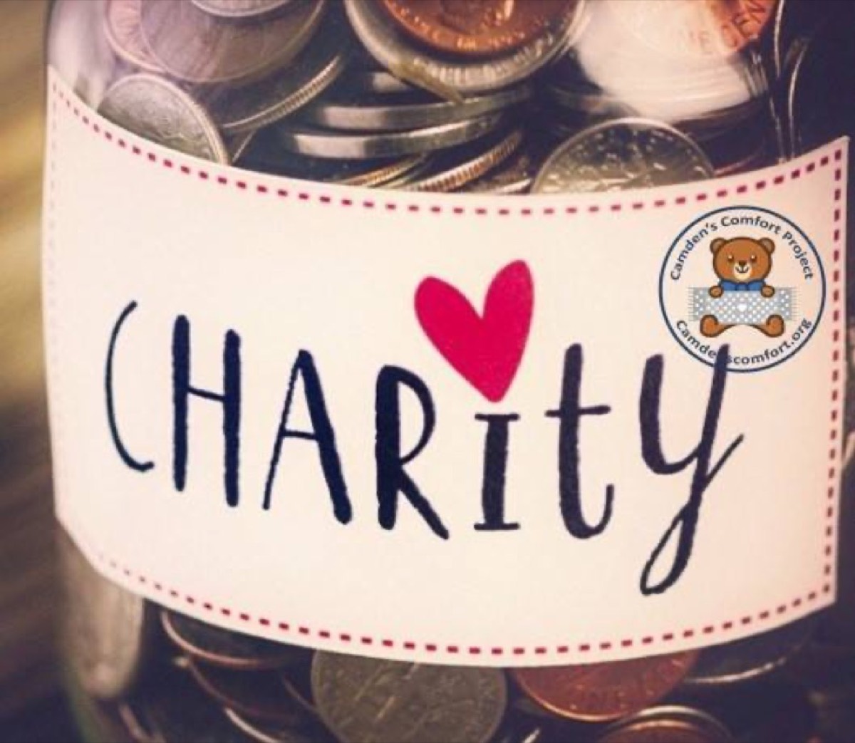 A charity jar of coins with the Camden's Comfort Project logo