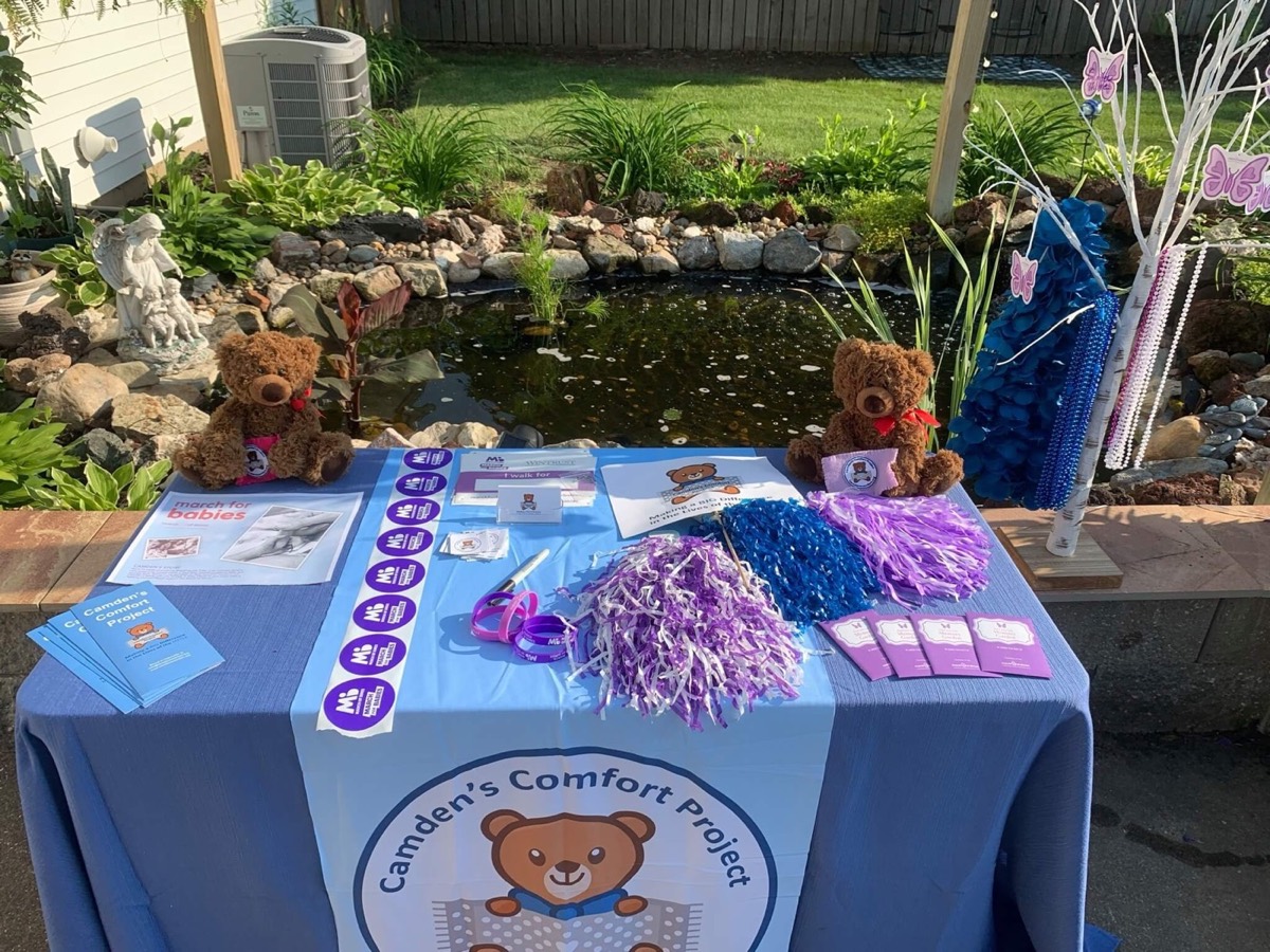 A Camden's Comfort Project table with teddy bears and handouts at a fundraiser