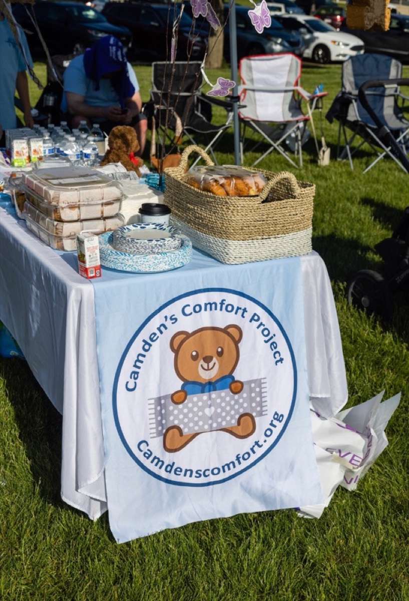 A Camden's Comfort Project table with handmade blankets at an outdoor event